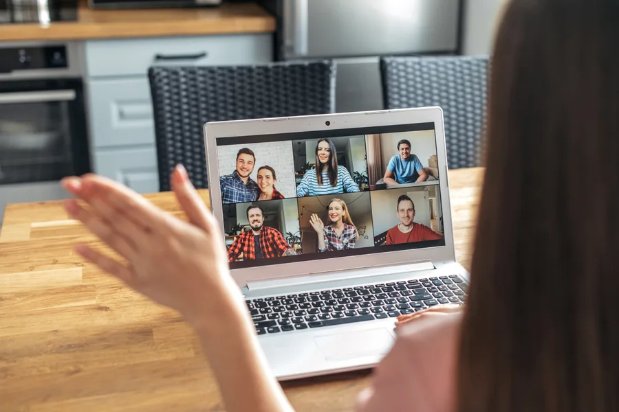 Waving hello on a video call from a laptop